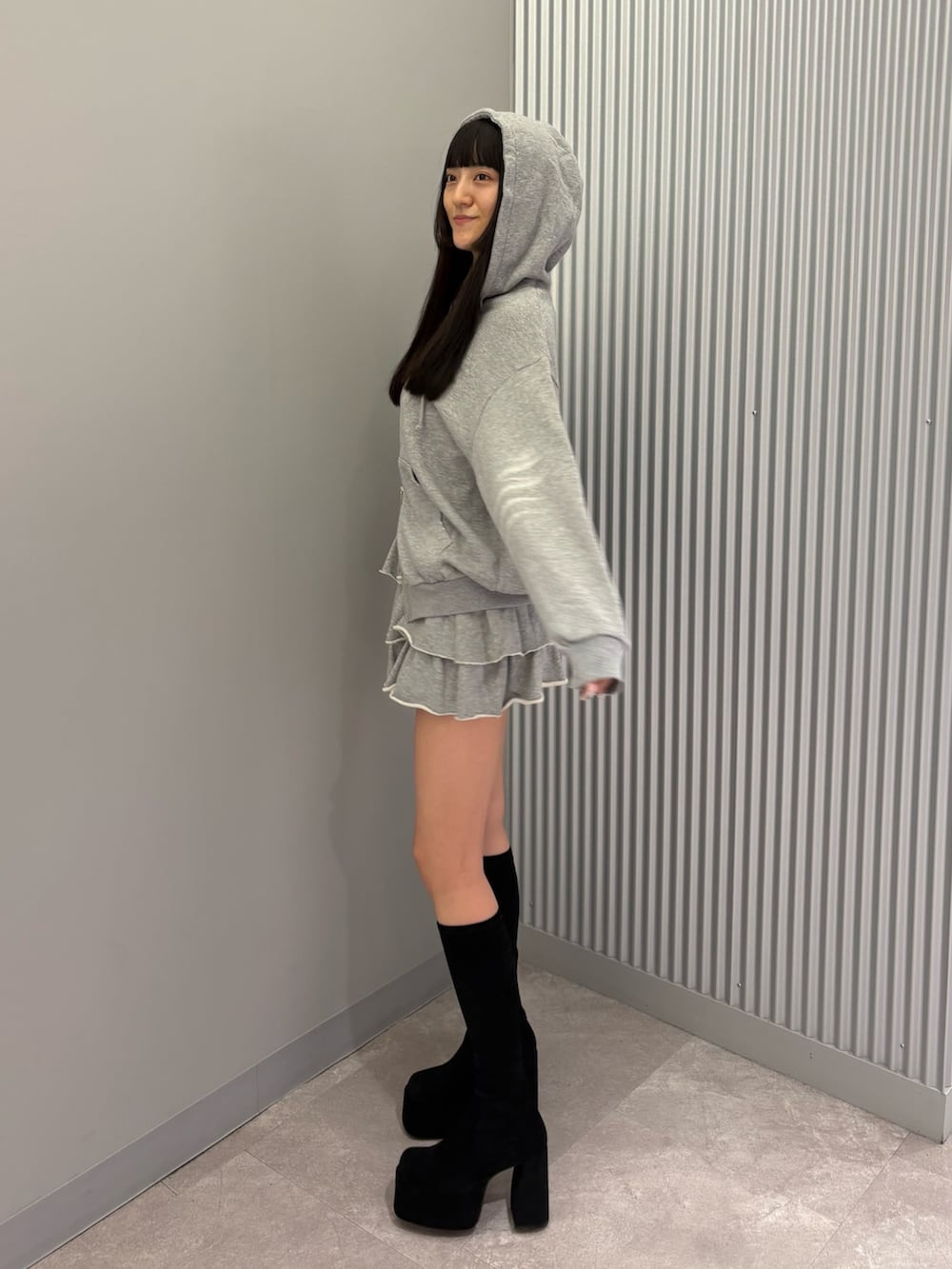 グレー系のスカート、グレー系のパーカー、ブラック系のブーツを着用したレディースの秋コーディネートの5枚目の写真