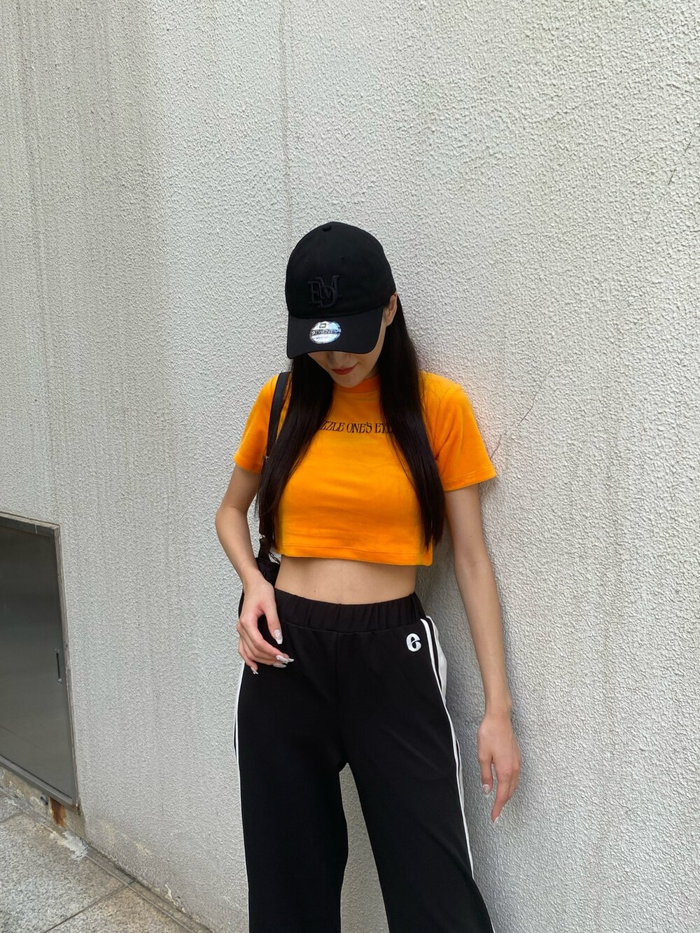 ブラック系のその他パンツ、ブラック系のハンドバッグ、オレンジ系のTシャツ/カットソーを着用したレディースの夏コーディネートの8枚目の写真