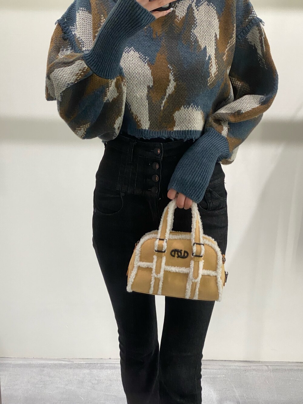 ベージュ系のハンドバッグ、ブラック系のデニムパンツ、ブルー系のニット/セーターを着用したレディースの秋コーディネートの5枚目の写真