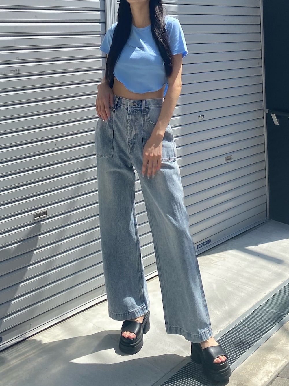 ブルー系のデニムパンツ、ブラック系のサンダル、ブラック系のハンドバッグを着用したレディースの夏コーディネートの3枚目の写真