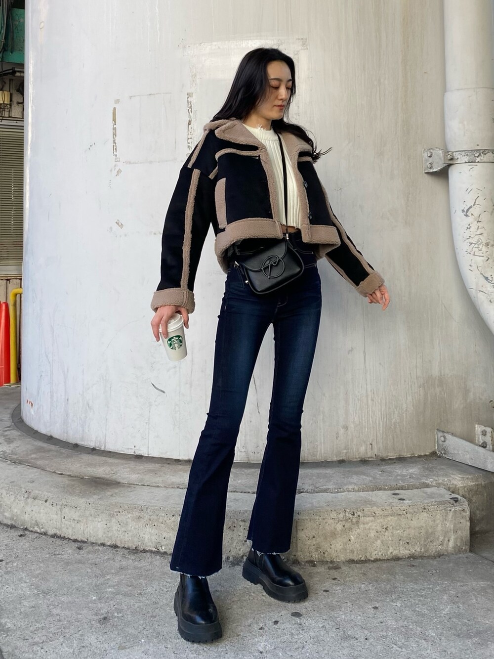 ブルー系のデニムパンツ、ブラック系のムートンコート、ホワイト系のニット/セーターを着用したレディースの秋コーディネートの2枚目の写真