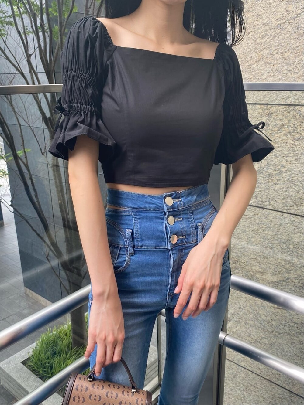 ブラック系のサンダル、その他のハンドバッグ、ブルー系のデニムパンツを着用したレディースの夏コーディネートの3枚目の写真
