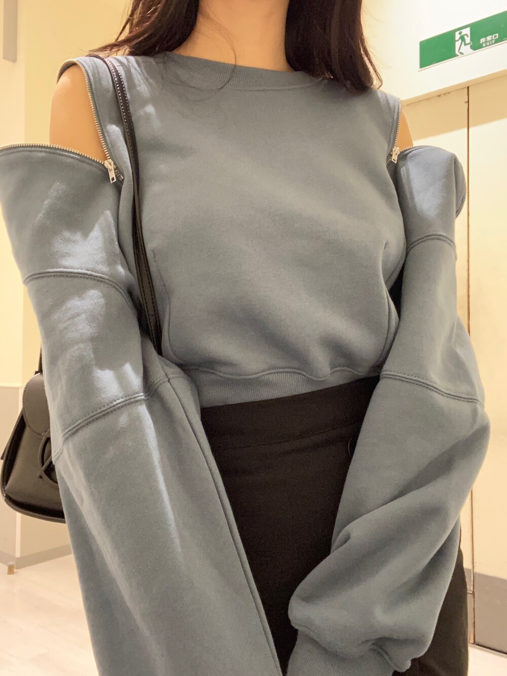 ブラック系のスカート、ブルー系のTシャツ/カットソー、ブラック系のショルダーバッグを着用したレディースの秋コーディネートの4枚目の写真