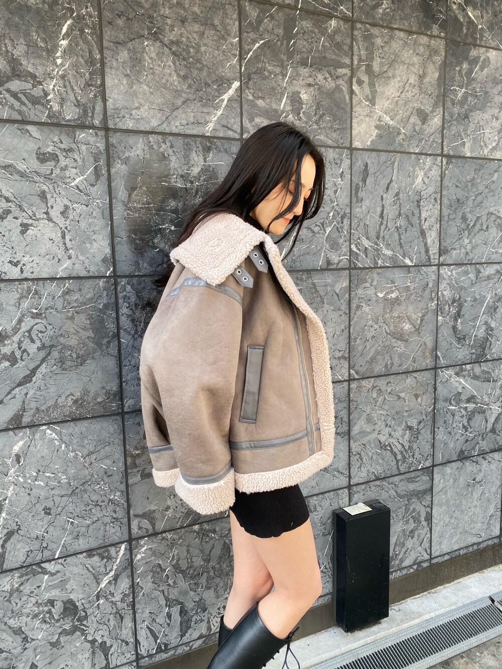 グレー系のブルゾン、ブラック系のワンピース、ブラック系のブーツを着用したレディースの冬コーディネートの4枚目の写真