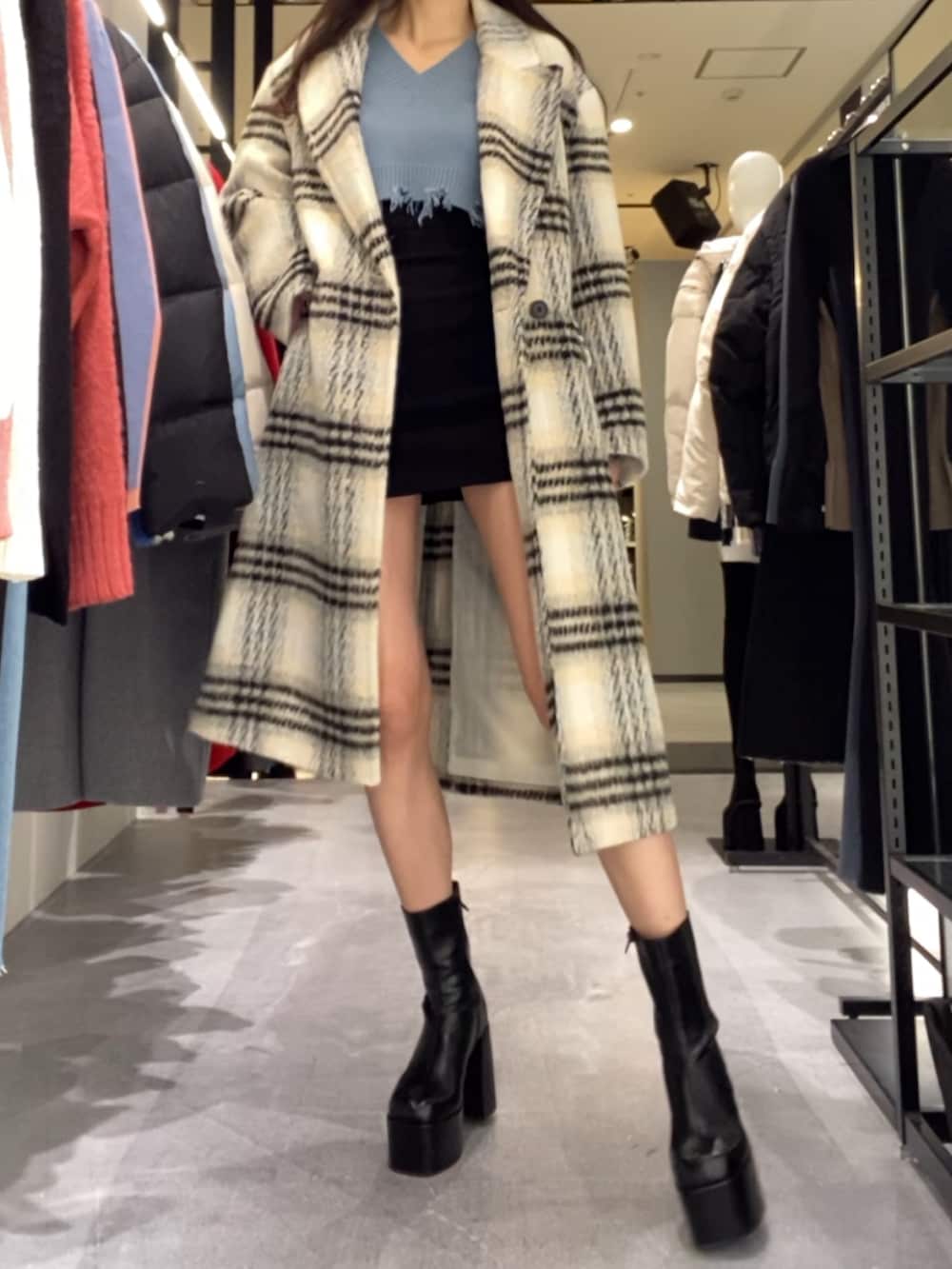 ブラック系のスカート、ブルー系のニット/セーター、その他のチェスターコートを着用したレディースの冬コーディネートの4枚目の写真