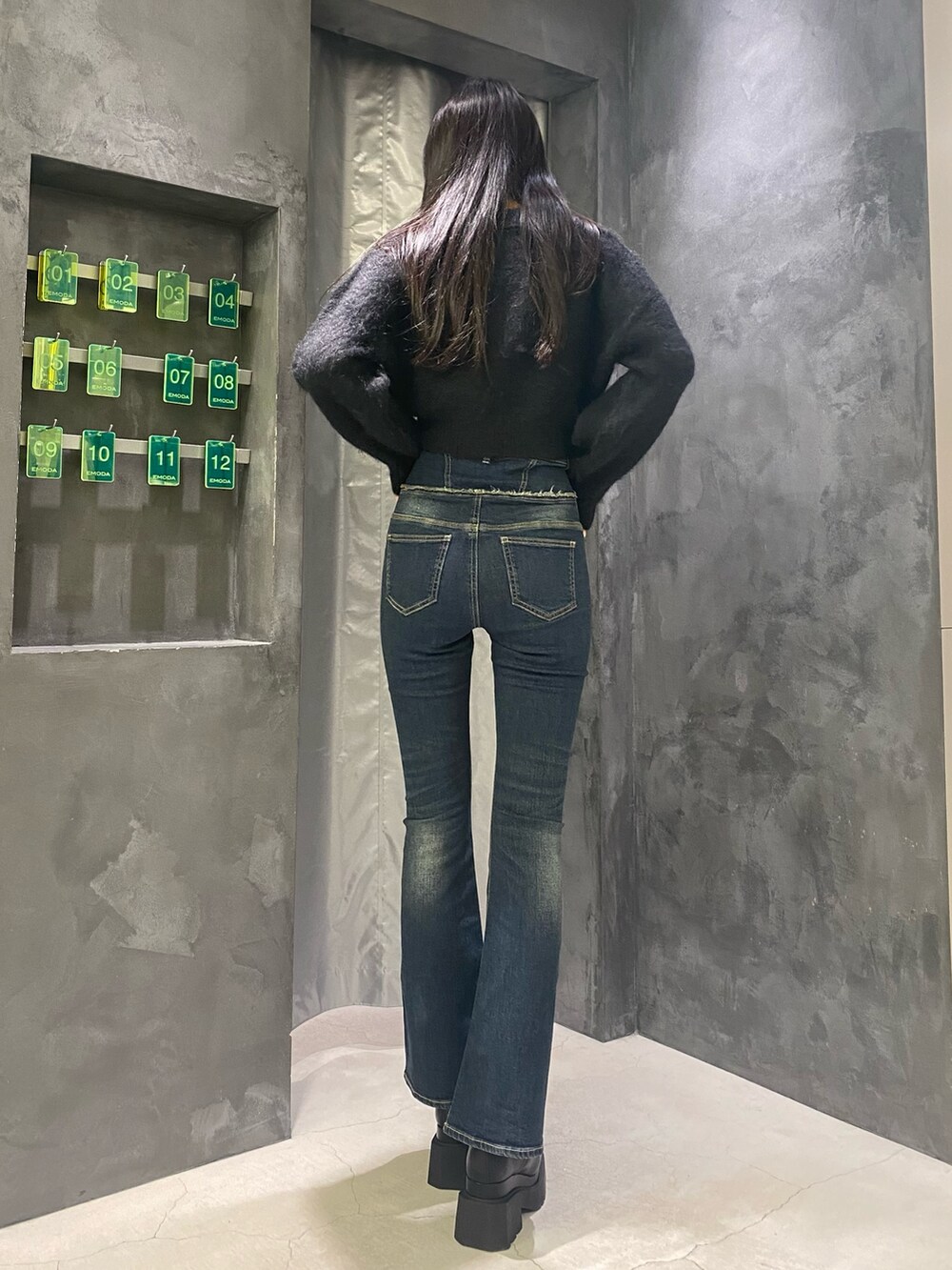 ブルー系のデニムパンツ、ブラック系のニット/セーター、ブラック系のブーツを着用したレディースの秋コーディネートの6枚目の写真