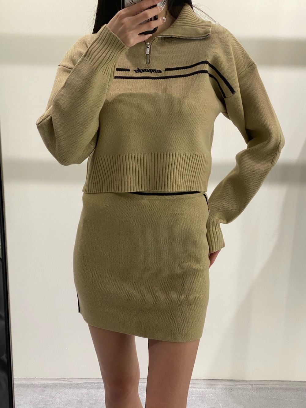 ベージュ系のニット/セーター、ベージュ系のスカート、ブラック系のブーツを着用したレディースの秋コーディネートの4枚目の写真