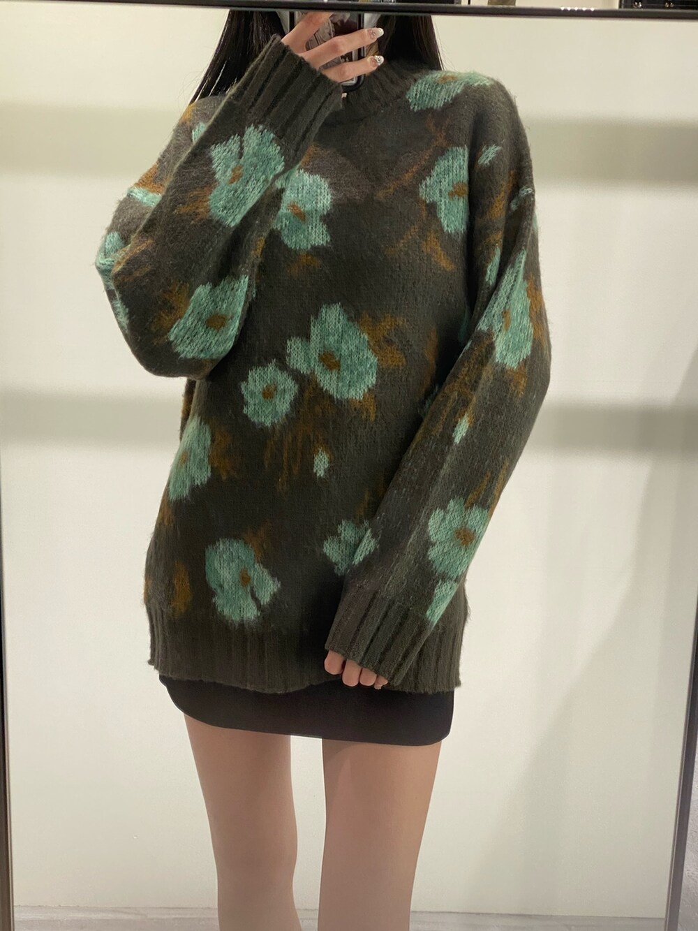 グリーン系のニット/セーター、ブラック系のスカート、ブラック系のブーツを着用したレディースの秋コーディネートの3枚目の写真