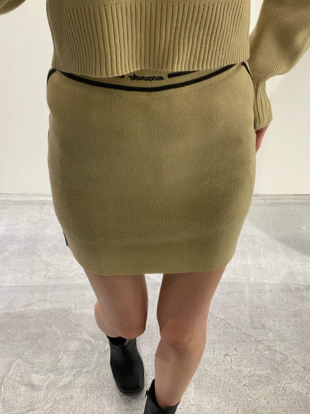 ベージュ系のニット/セーター、ベージュ系のスカート、ブラック系のブーツを着用したレディースの秋コーディネートの7枚目の写真