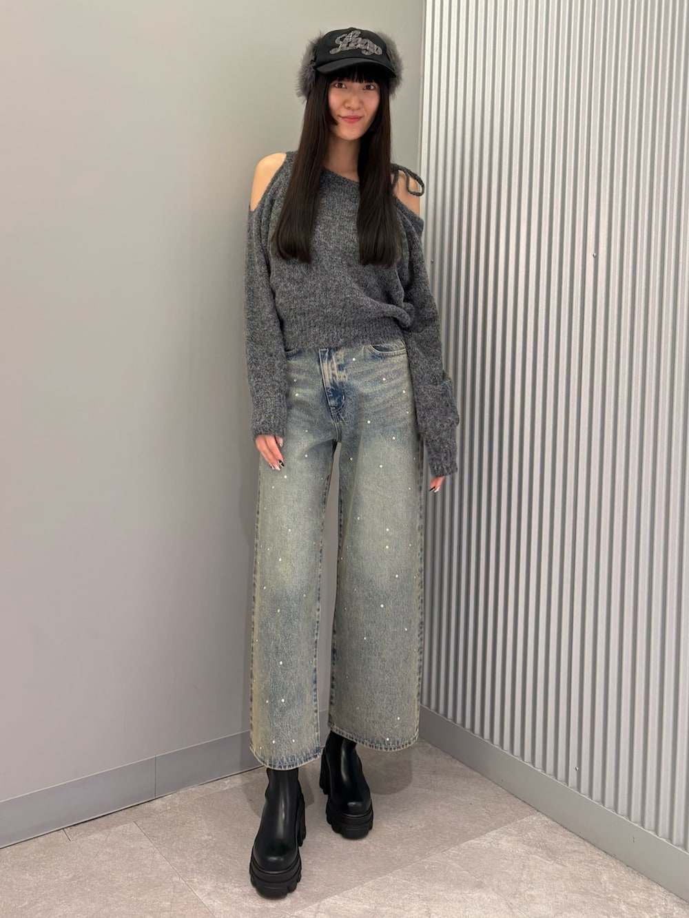 ブルー系のデニムパンツ、グレー系のニット/セーター、ブラック系のブーツを着用したレディースの冬コーディネートの2枚目の写真