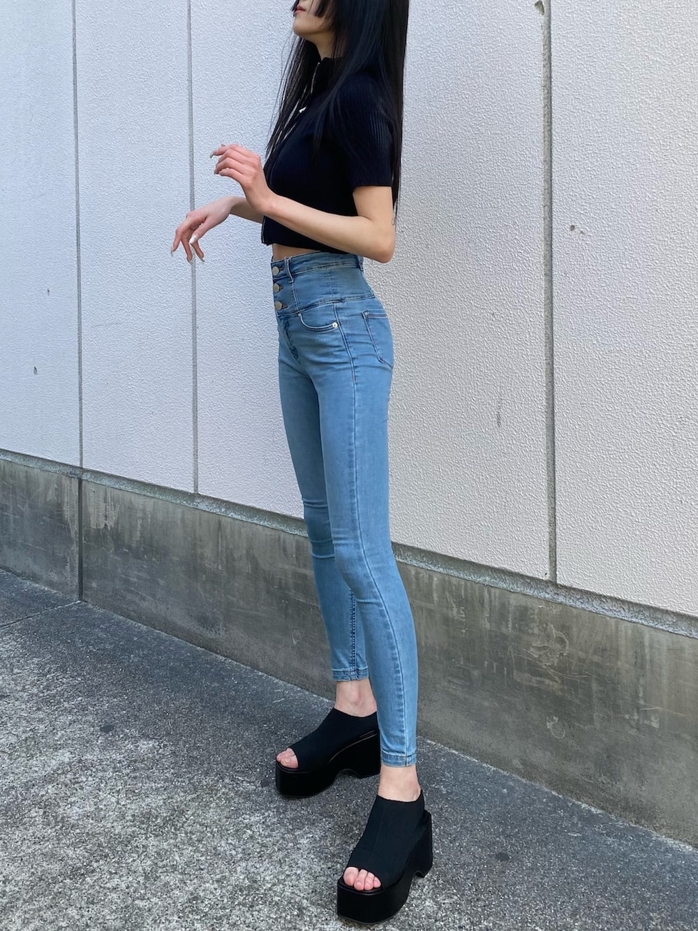 ブラック系のニット/セーター、ブルー系のデニムパンツ、ブラック系のサンダルを着用したレディースの春コーディネートの3枚目の写真