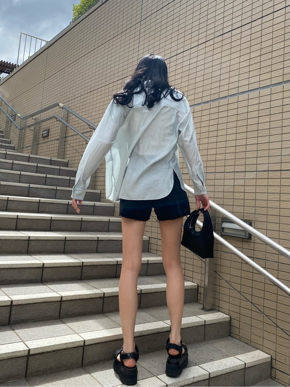 ブラック系のサンダル、ホワイト系のタンクトップ、ブラック系のデニムパンツを着用したレディースの夏コーディネートの2枚目の写真