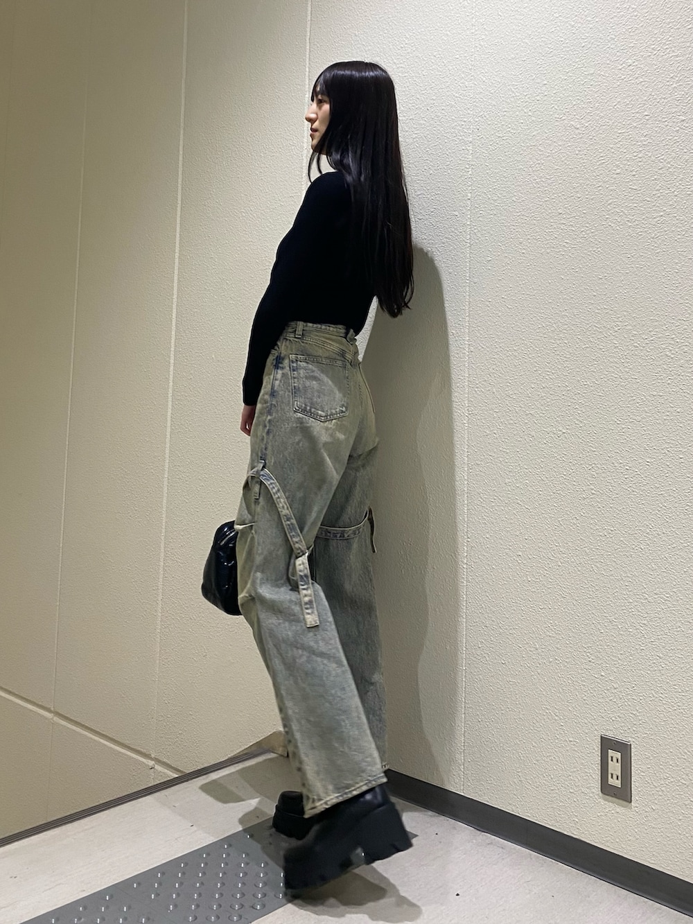 ブルー系のデニムパンツ、ブラック系のニット/セーター、ブラック系のボストンバッグを着用したレディースの冬コーディネートの2枚目の写真