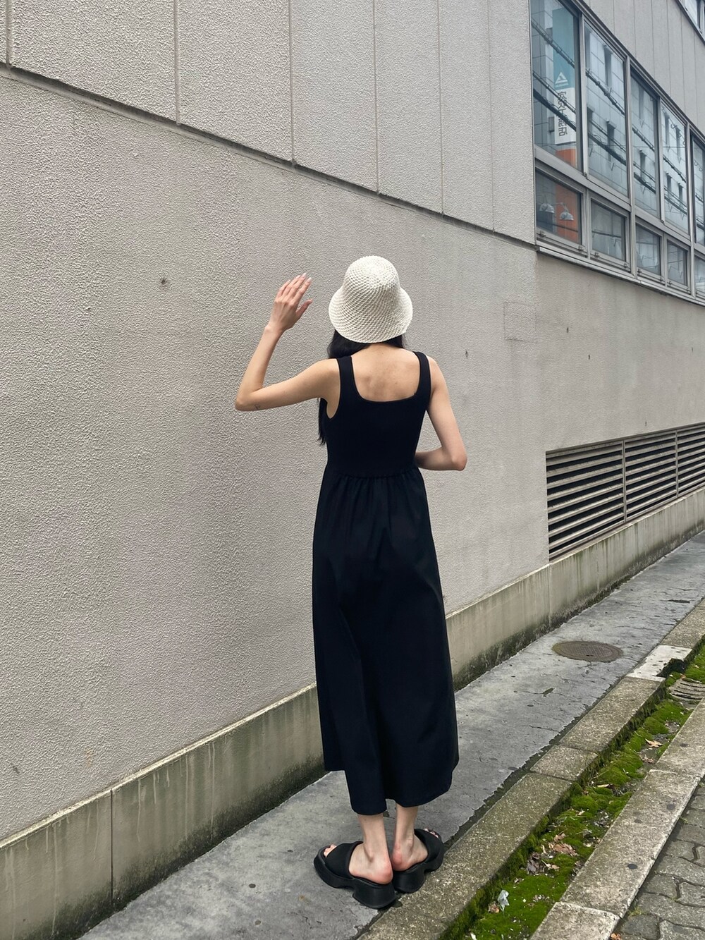 ブラック系のワンピース、ブラック系のサンダル、ホワイト系のハットを着用したレディースの夏コーディネートの4枚目の写真