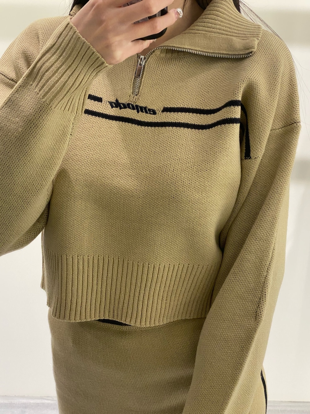 ベージュ系のニット/セーター、ベージュ系のスカート、ブラック系のブーツを着用したレディースの秋コーディネートの5枚目の写真