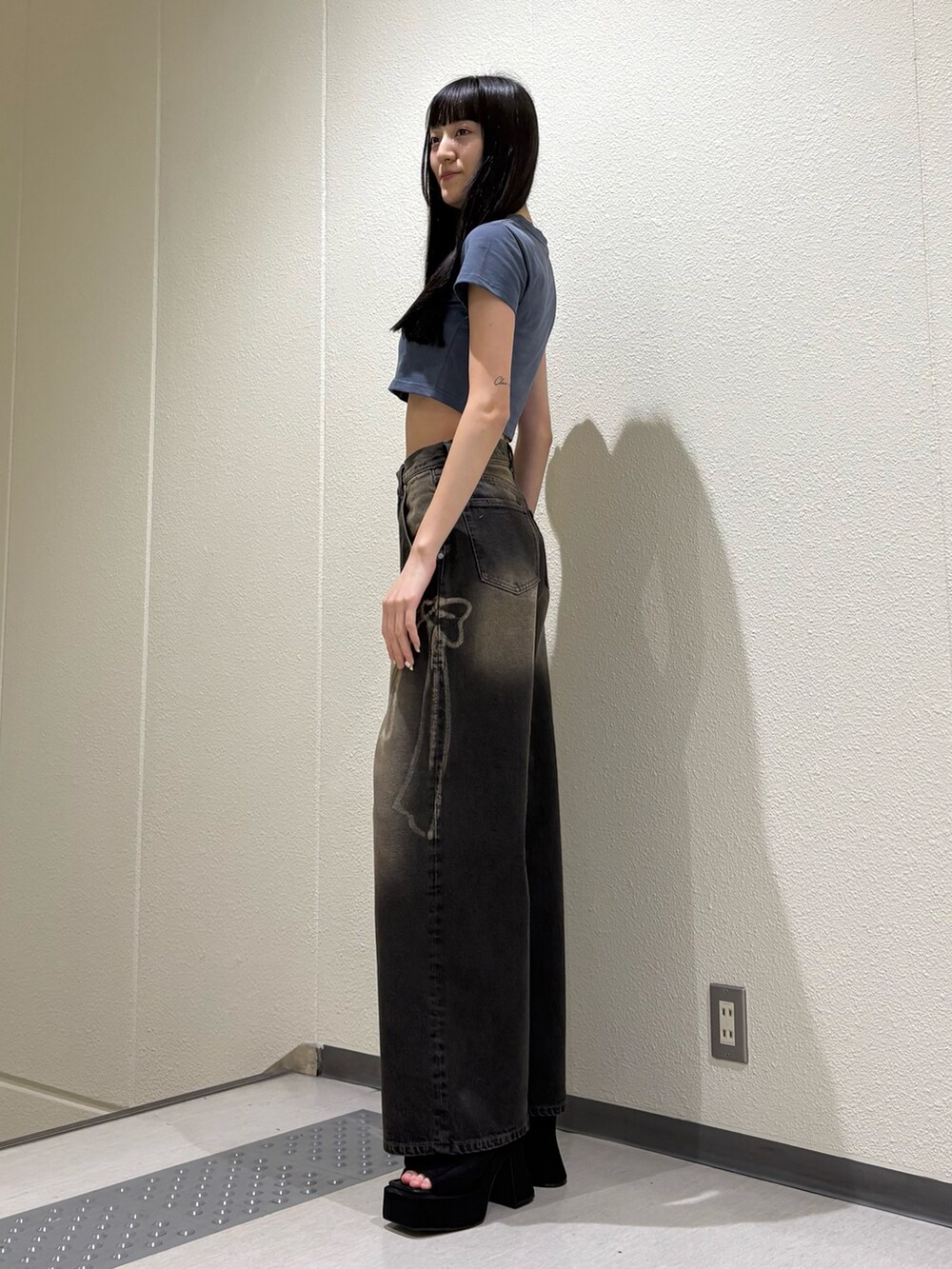 ブラック系のデニムパンツ、ブルー系のTシャツ/カットソー、ブラック系のサンダルを着用したレディースの夏コーディネートの2枚目の写真