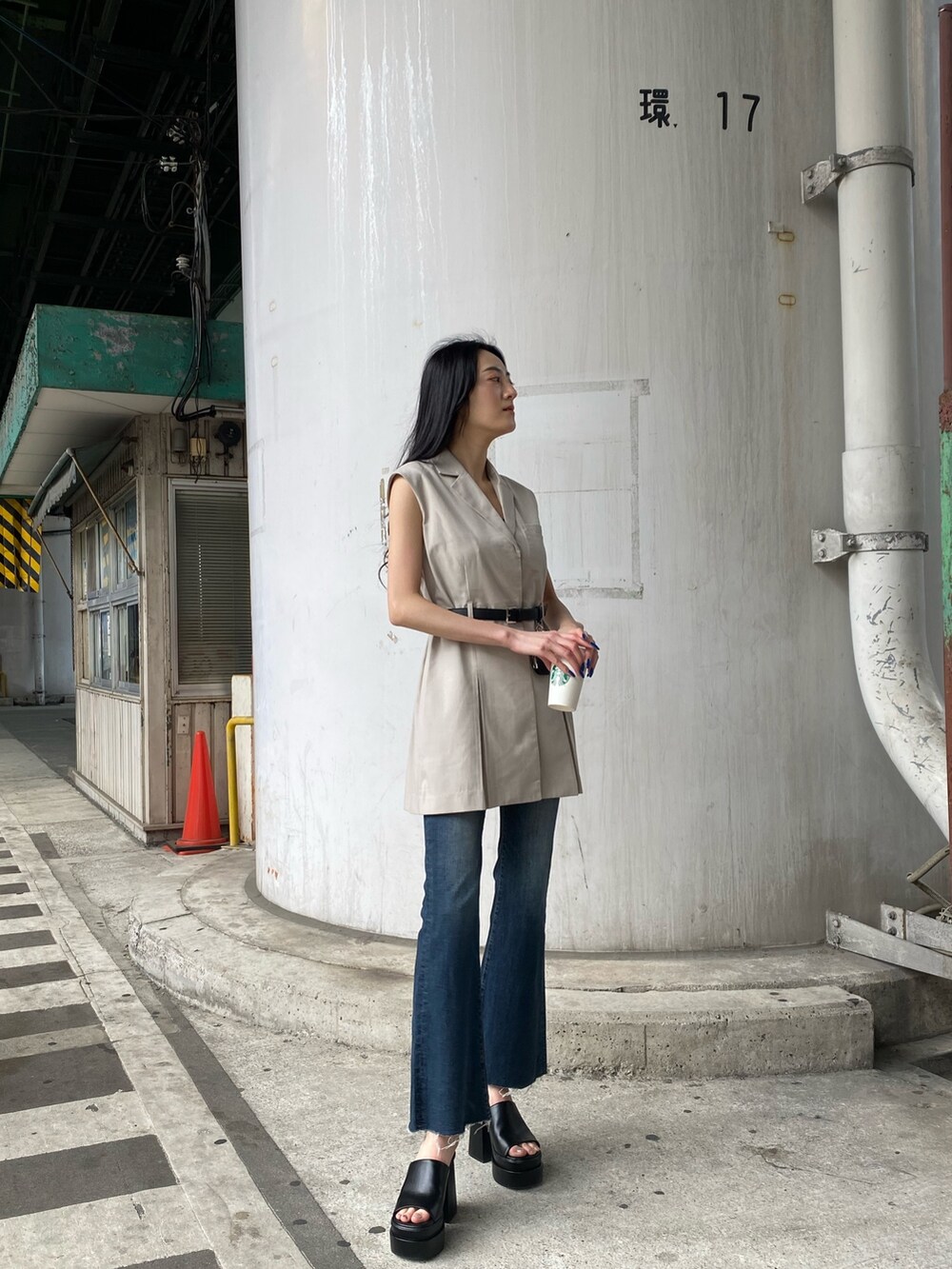 ホワイト系のワンピース、ブルー系のデニムパンツ、ブラック系のサンダルを着用したレディースの春コーディネートの2枚目の写真