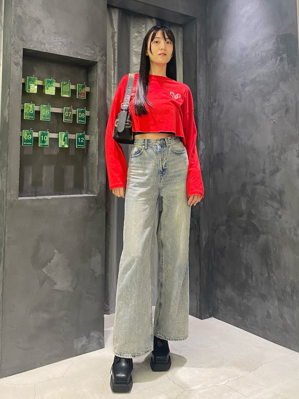 ブルー系のデニムパンツ、ブラック系のハンドバッグ、レッド系のTシャツ/カットソーを着用したレディースの秋コーディネートの2枚目の写真