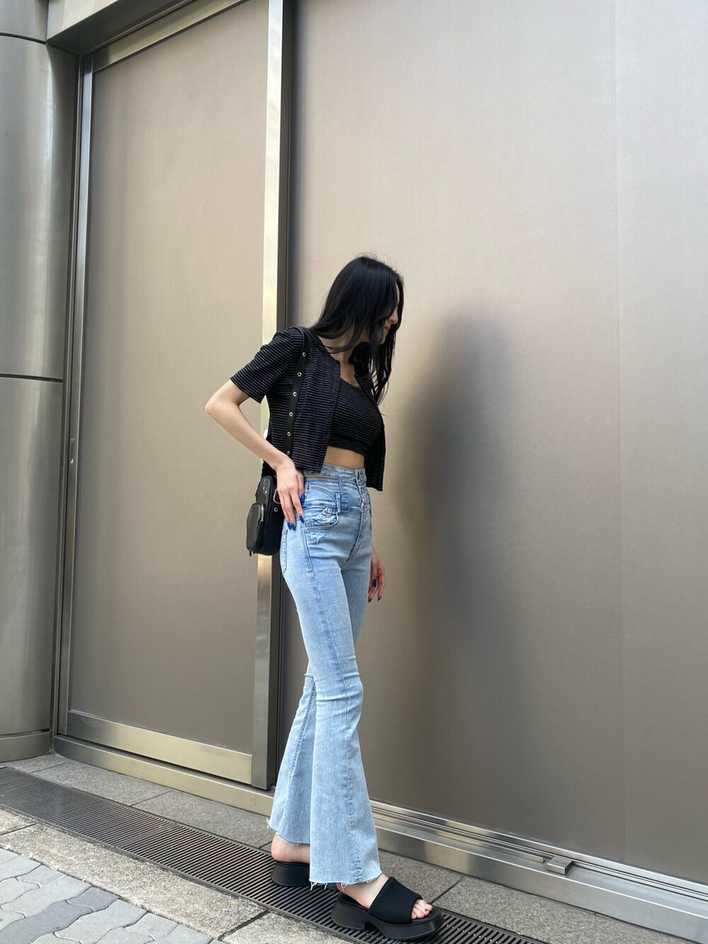 ブラック系のアンサンブル、ブルー系のデニムパンツ、ブラック系のサンダルを着用したレディースの春コーディネートの4枚目の写真