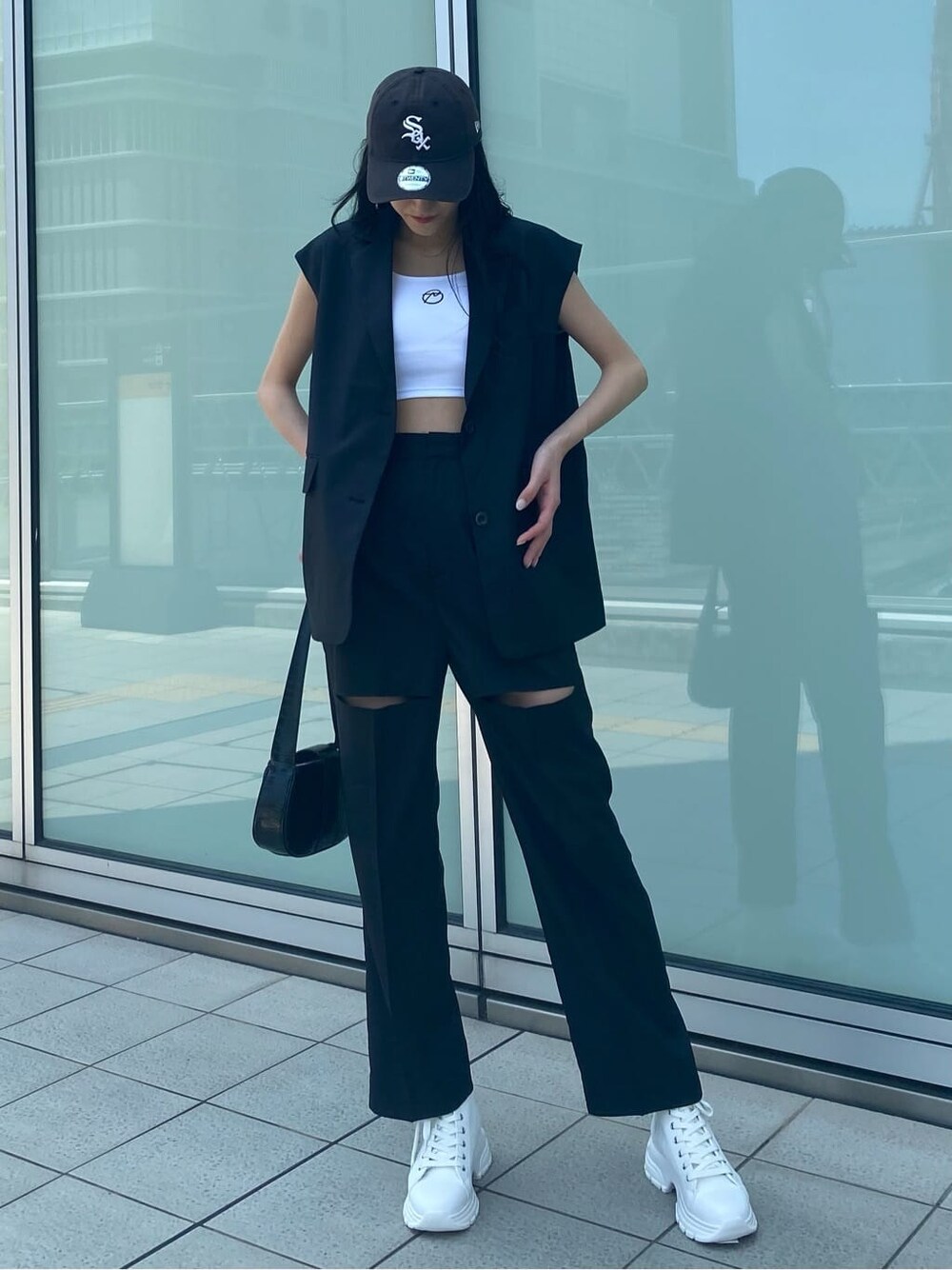 ホワイト系のスニーカー、ブラック系のベスト、ブラック系のその他パンツを着用したレディースの夏コーディネートの4枚目の写真