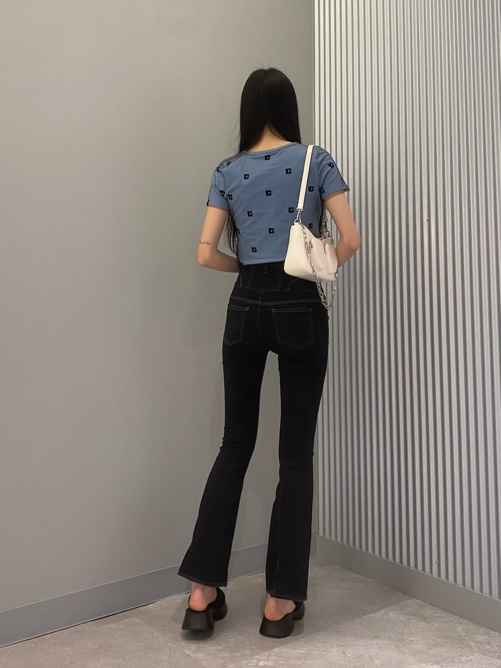 ブラック系のデニムパンツ、ブルー系のTシャツ/カットソー、ホワイト系のショルダーバッグを着用したレディースの春コーディネートの2枚目の写真