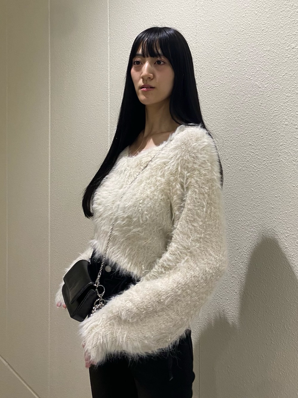 ホワイト系のニット/セーター、ブラック系のブーツ、ブラック系のデニムパンツを着用したレディースの冬コーディネートの7枚目の写真