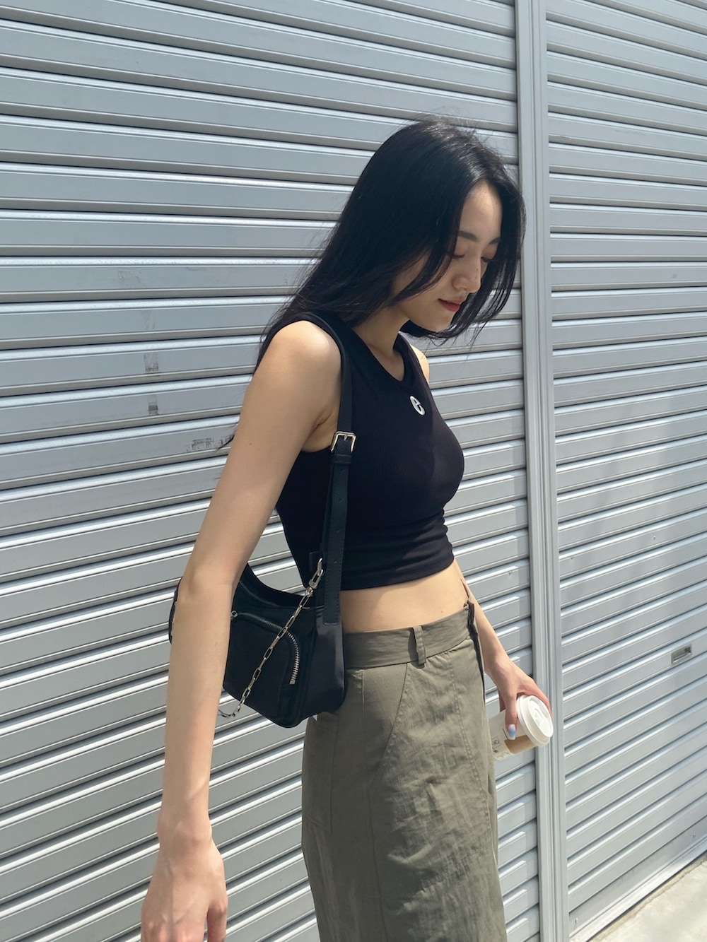 ベージュ系のカーゴパンツ、ブラック系のタンクトップ、ブラック系のハンドバッグを着用したレディースの夏コーディネートの4枚目の写真