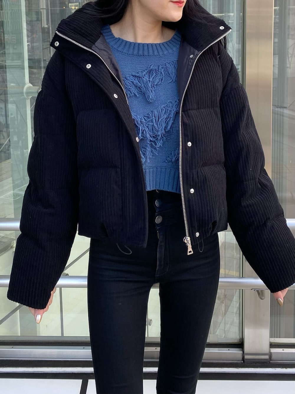 ブラック系のデニムパンツ、ブラック系のダウンジャケット/コート、ブルー系のニット/セーターを着用したレディースの冬コーディネートの5枚目の写真