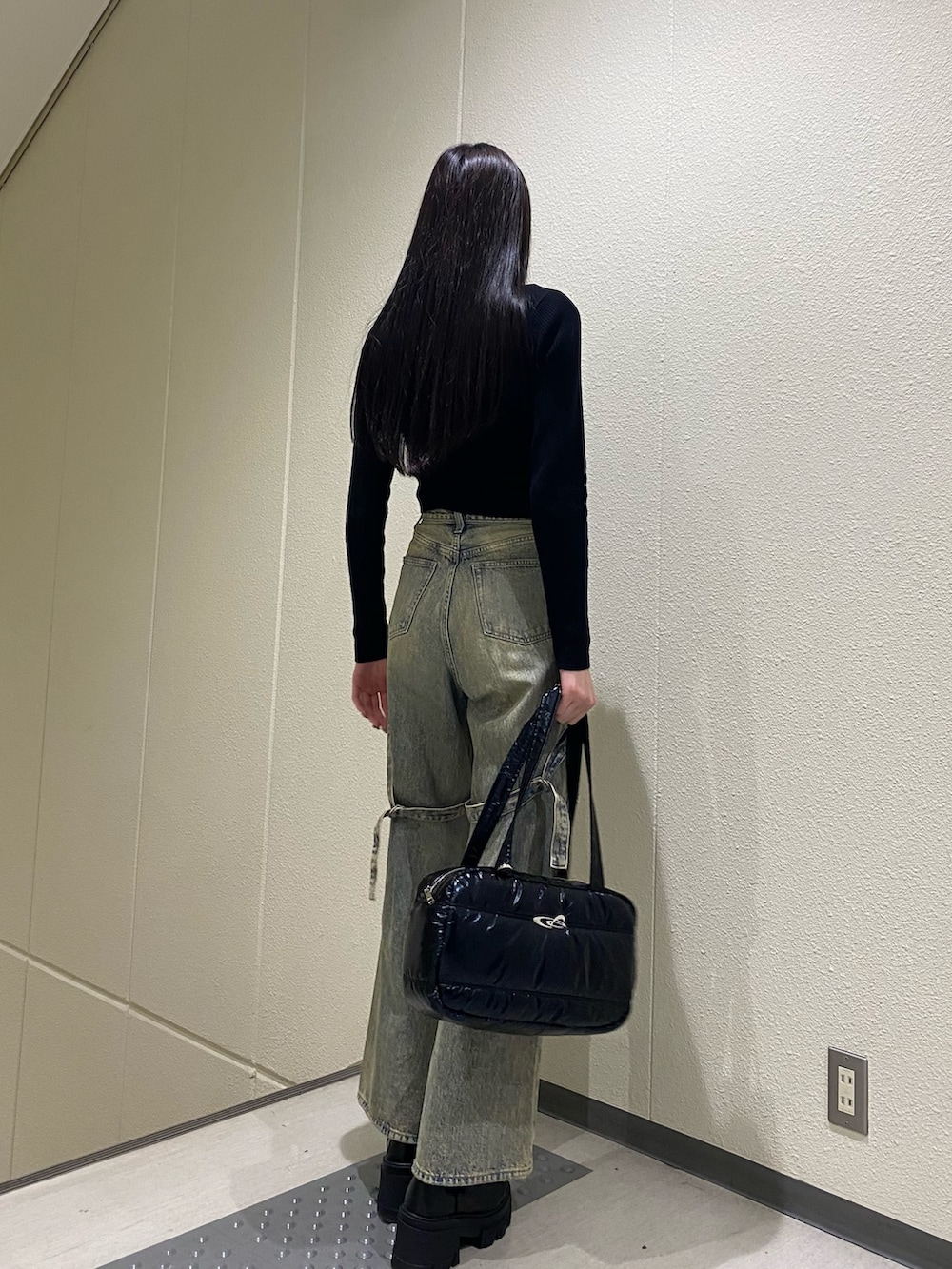 ブルー系のデニムパンツ、ブラック系のニット/セーター、ブラック系のボストンバッグを着用したレディースの冬コーディネートの3枚目の写真