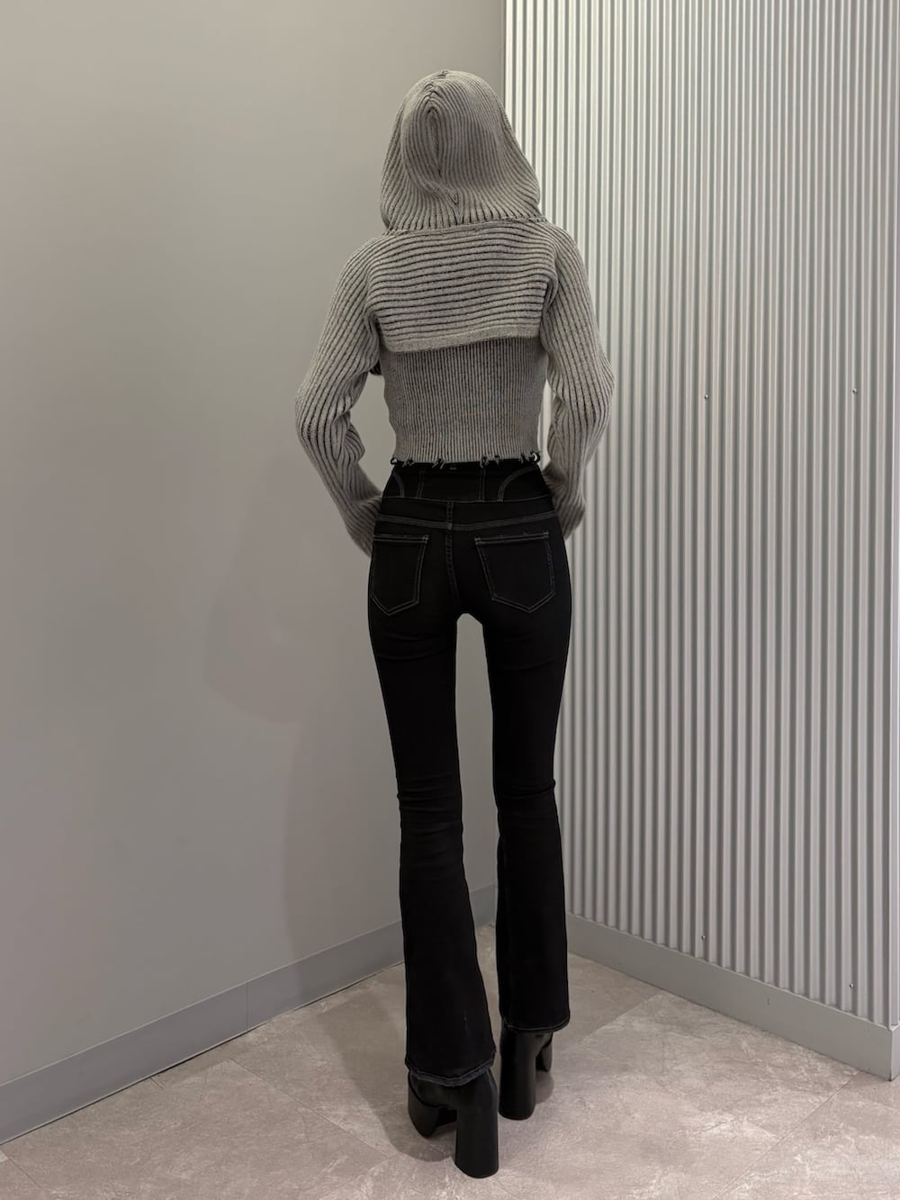 ブラック系のデニムパンツ、ブラック系のブーツ、グレー系のニット/セーターを着用したレディースの秋コーディネートの4枚目の写真