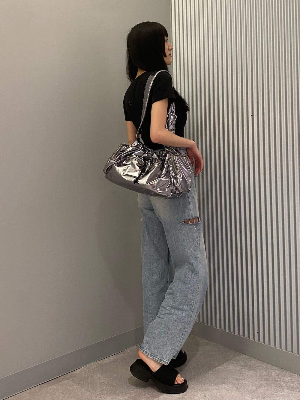 ブラック系のTシャツ/カットソー、ブラック系のサンダル、ブルー系のデニムパンツを着用したレディースの夏コーディネートの2枚目の写真