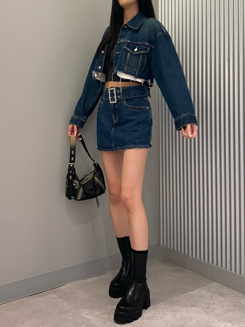 ブルー系のデニムジャケット、ブルー系のデニムスカート、ブラック系のハンドバッグを着用したレディースの夏コーディネートの3枚目の写真