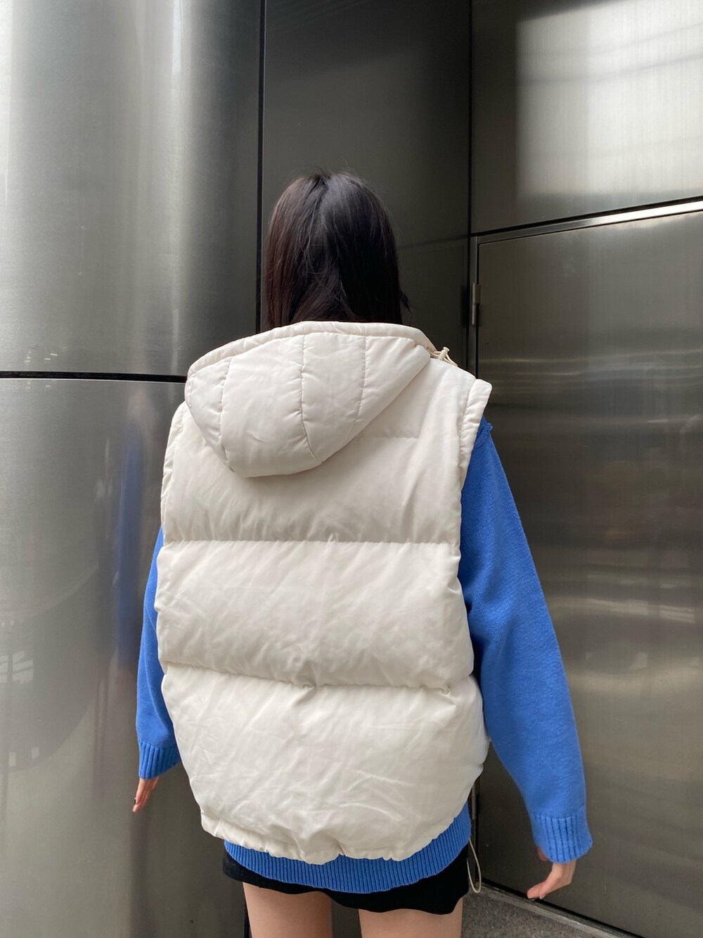 ブルー系のニット/セーター、ホワイト系のダウンジャケット/コート、ブラック系のスカートを着用したレディースの冬コーディネートの6枚目の写真
