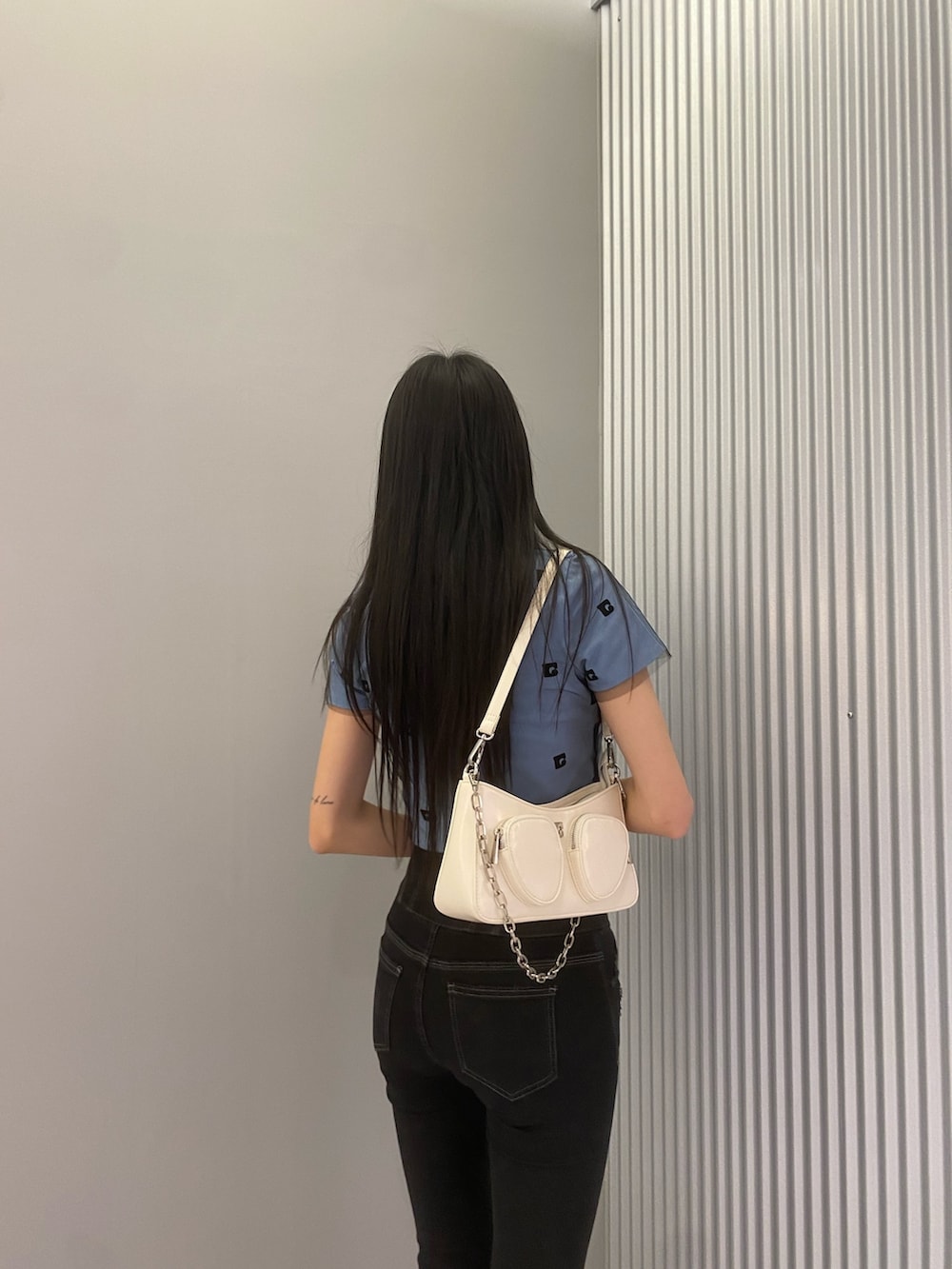 ブラック系のデニムパンツ、ブルー系のTシャツ/カットソー、ホワイト系のショルダーバッグを着用したレディースの春コーディネートの5枚目の写真