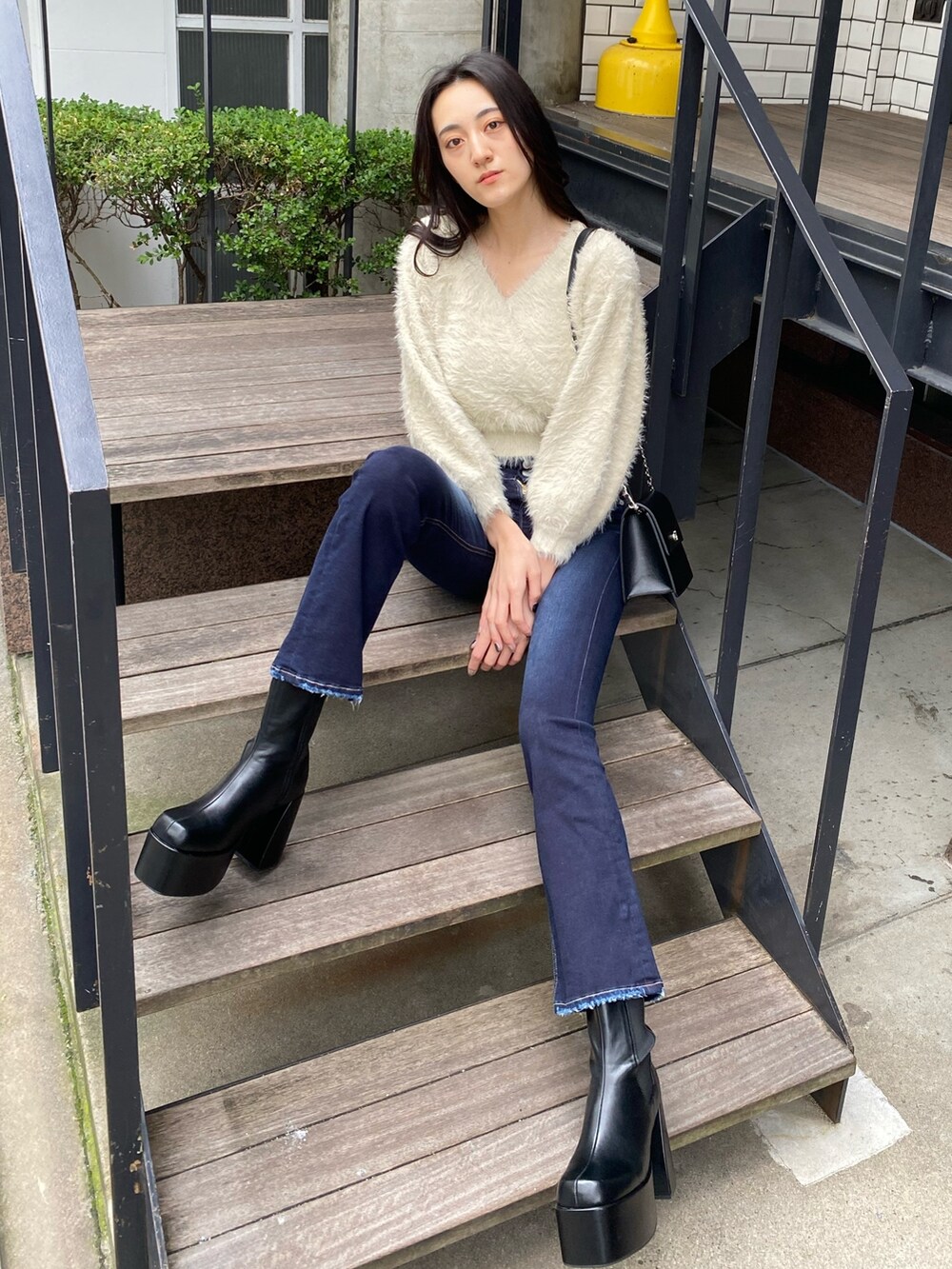 ブラック系のハンドバッグ、ブルー系のデニムパンツ、ホワイト系のニット/セーターを着用したレディースの冬コーディネートの2枚目の写真