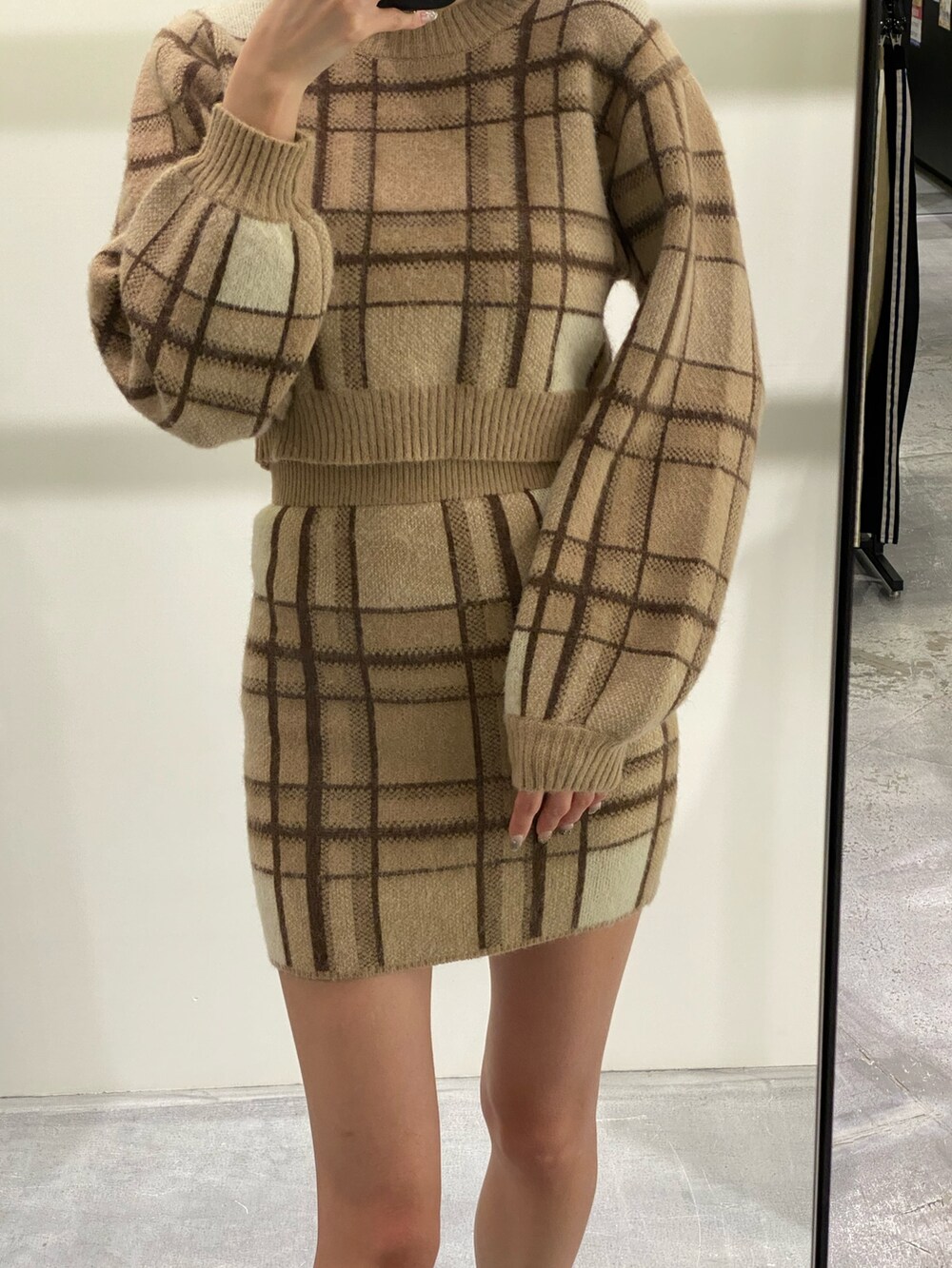 ベージュ系のニット/セーター、ベージュ系のスカート、ブラック系のブーツを着用したレディースの冬コーディネートの2枚目の写真