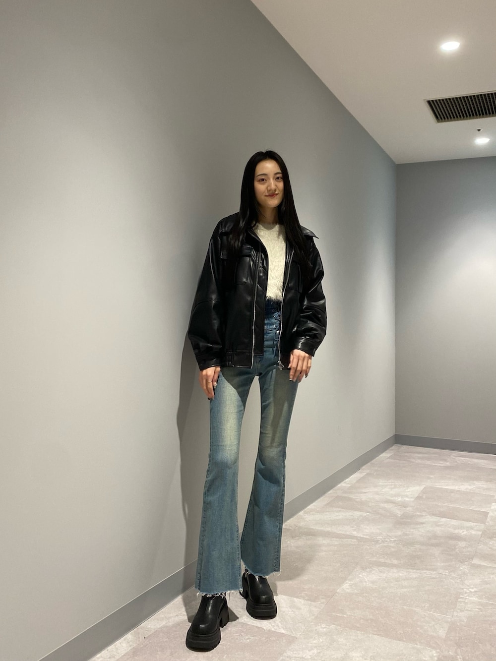 ブラック系のブルゾン、ブルー系のデニムパンツ、ホワイト系のニット/セーターを着用したレディースの冬コーディネートの3枚目の写真