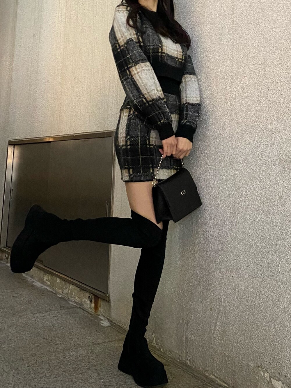 ブラック系のスカート、ブラック系のニット/セーター、ブラック系のブーツを着用したレディースの冬コーディネートの4枚目の写真