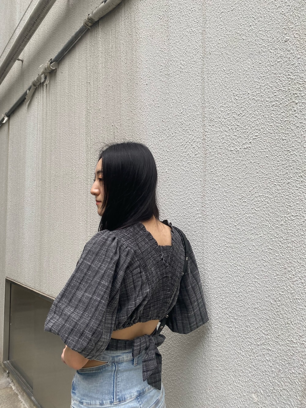 ブラック系のショルダーバッグ、ブラック系のTシャツ/カットソー、ブルー系のデニムパンツを着用したレディースの夏コーディネートの6枚目の写真