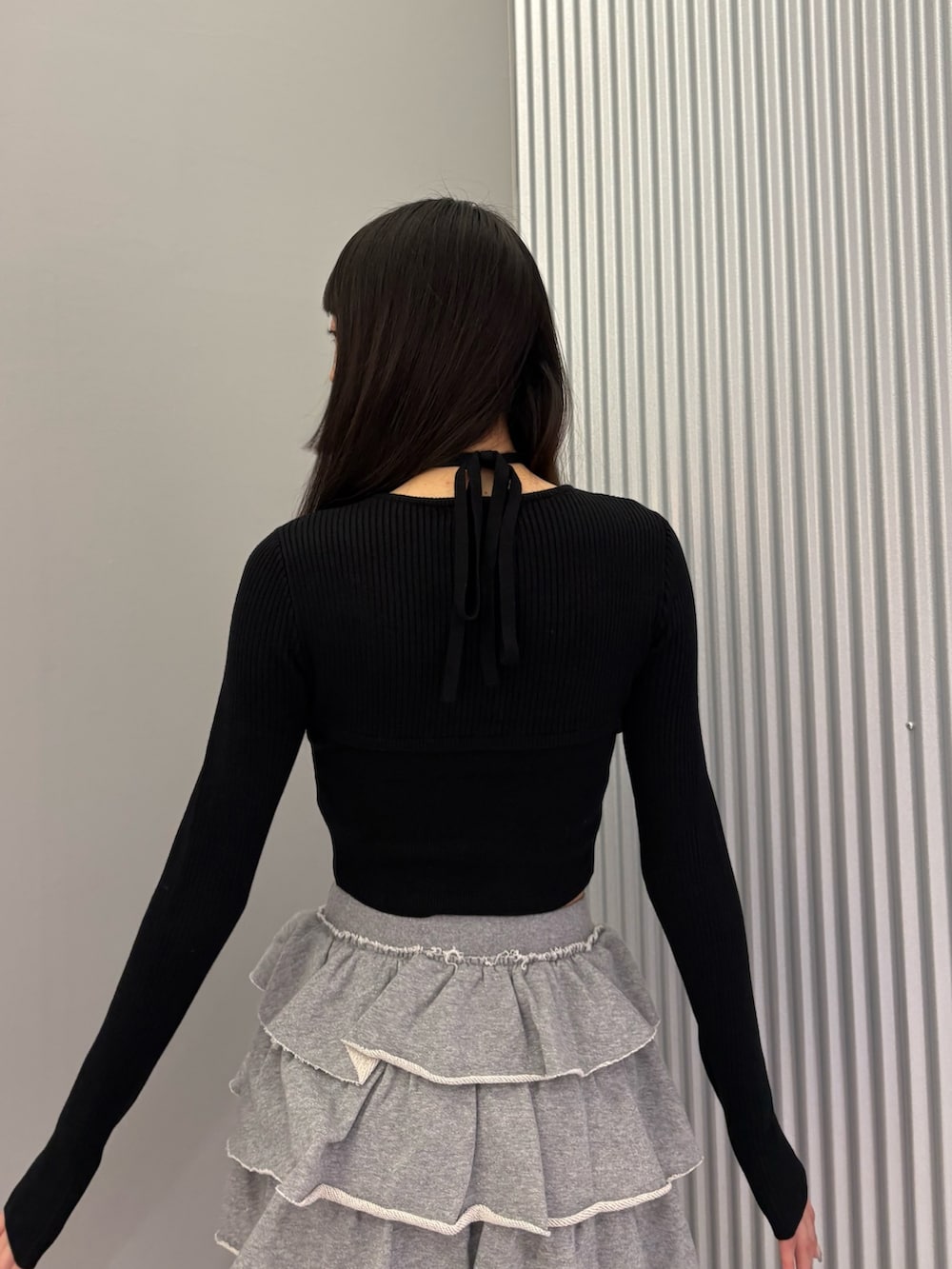 グレー系のスカート、ブラック系のニット/セーター、ブラック系のブーツを着用したレディースの秋コーディネートの7枚目の写真