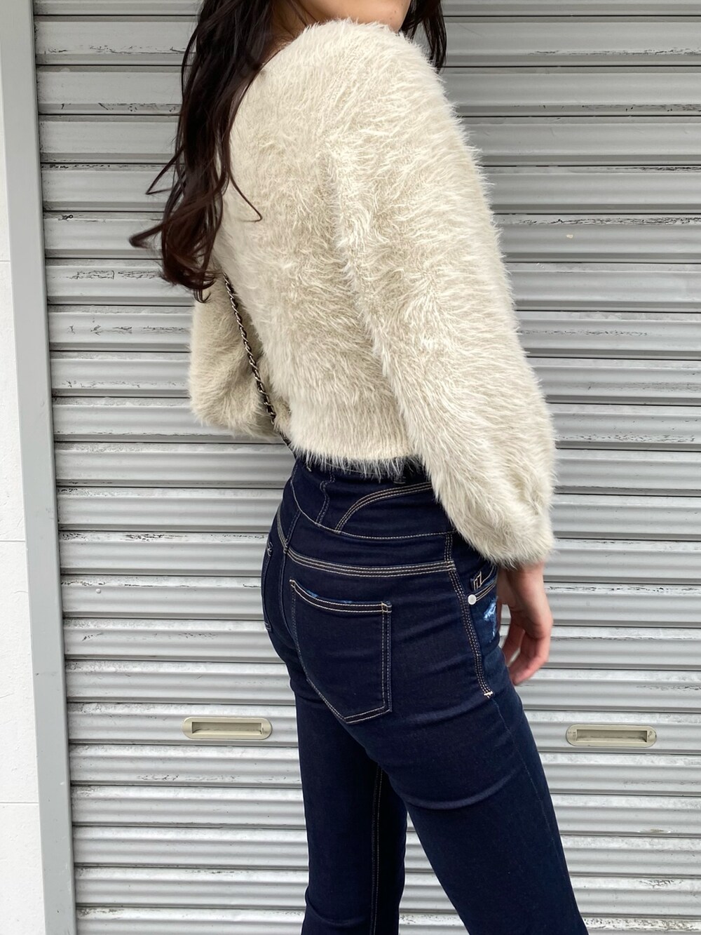 ブラック系のハンドバッグ、ブルー系のデニムパンツ、ホワイト系のニット/セーターを着用したレディースの冬コーディネートの7枚目の写真