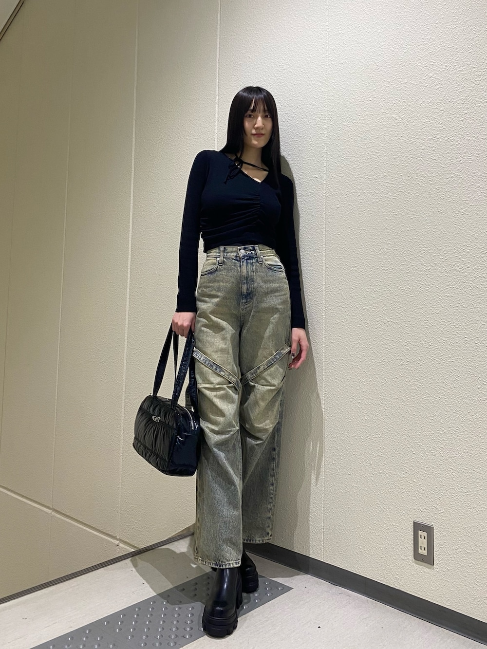 ブルー系のデニムパンツ、ブラック系のニット/セーター、ブラック系のボストンバッグを着用したレディースの冬コーディネートの4枚目の写真