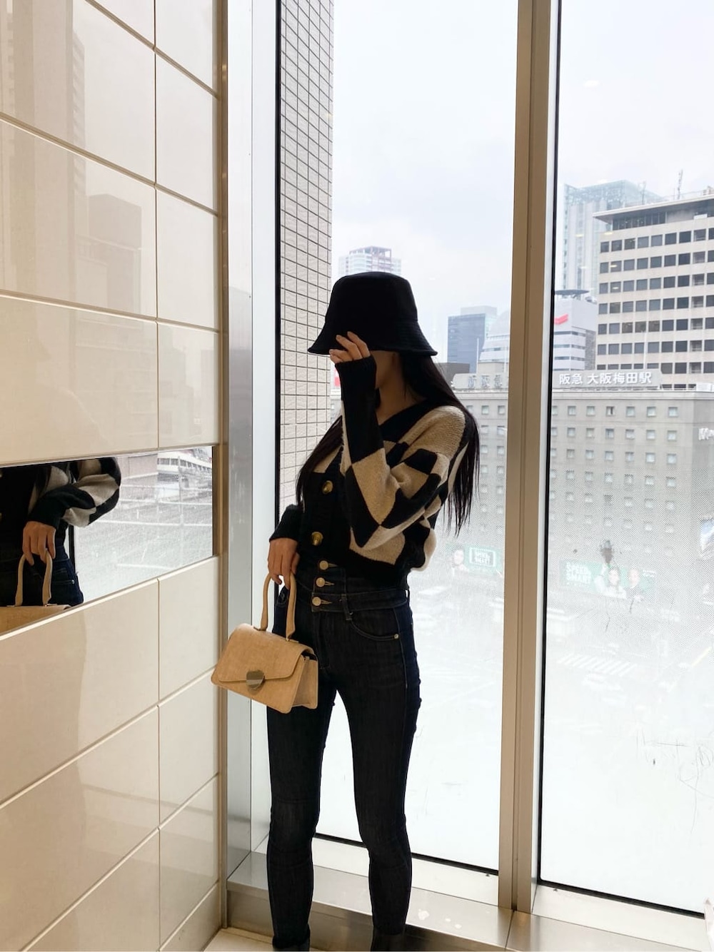 ブルー系のデニムパンツ、ブラック系のカーディガン/ボレロ、ベージュ系のハンドバッグを着用したレディースの冬コーディネートの4枚目の写真