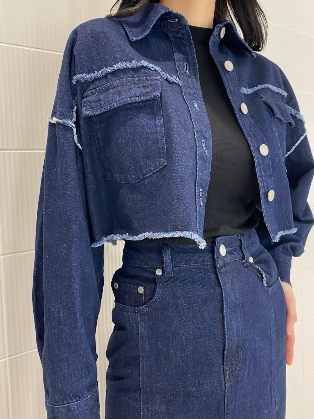 ブルー系のデニムジャケット、ブルー系のスカート、ホワイト系のハンドバッグを着用したレディースの夏コーディネートの6枚目の写真