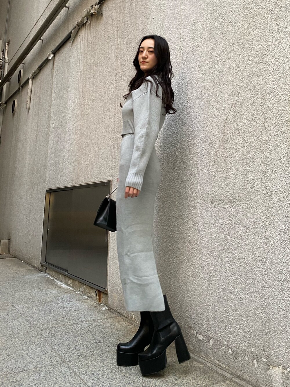 ブラック系のハンドバッグ、グレー系のスカート、グレー系のニット/セーターを着用したレディースの冬コーディネートの2枚目の写真