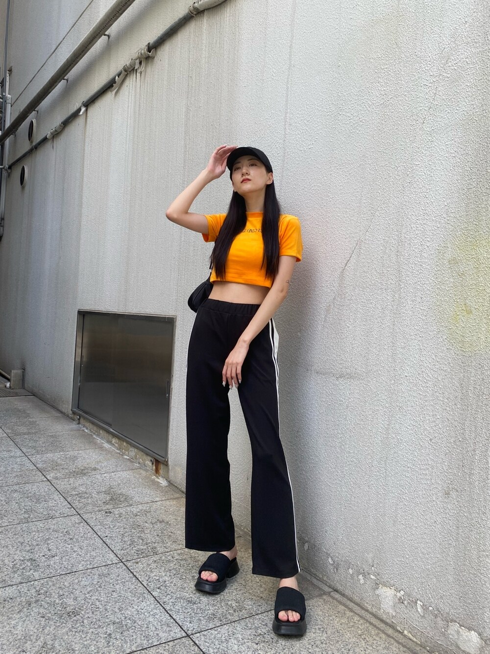 ブラック系のその他パンツ、ブラック系のハンドバッグ、オレンジ系のTシャツ/カットソーを着用したレディースの夏コーディネートの3枚目の写真