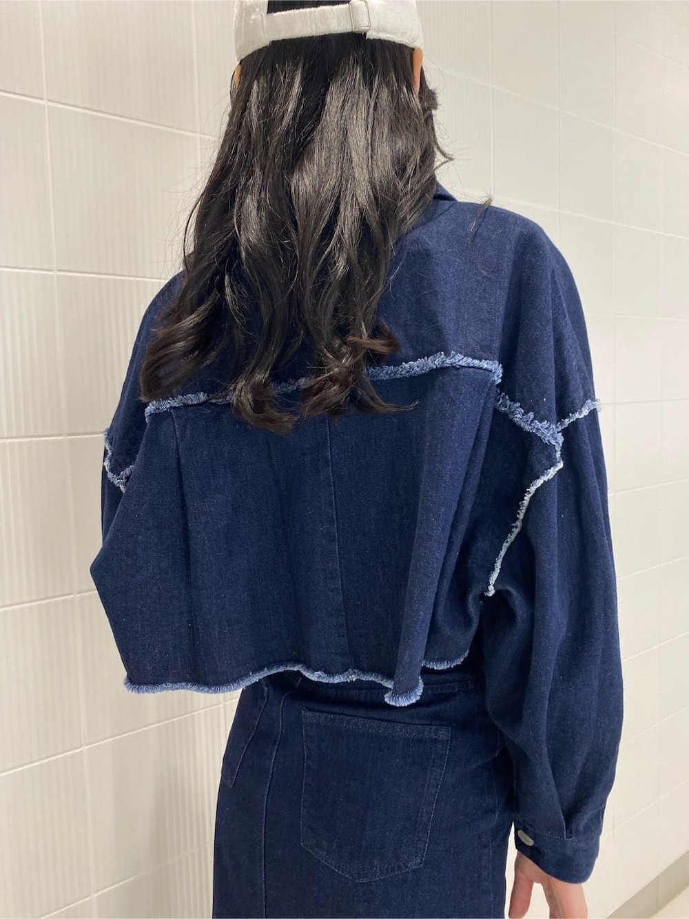 ブルー系のデニムジャケット、ブルー系のスカート、ホワイト系のハンドバッグを着用したレディースの夏コーディネートの7枚目の写真