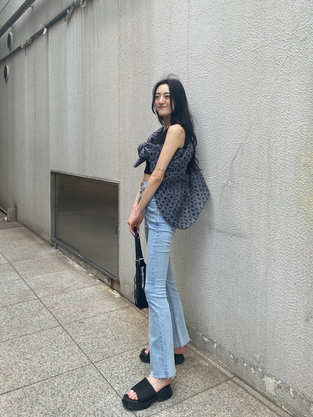 ブルー系のデニムパンツ、ブラック系のハンドバッグ、ブラック系のサンダルを着用したレディースの夏コーディネートの5枚目の写真