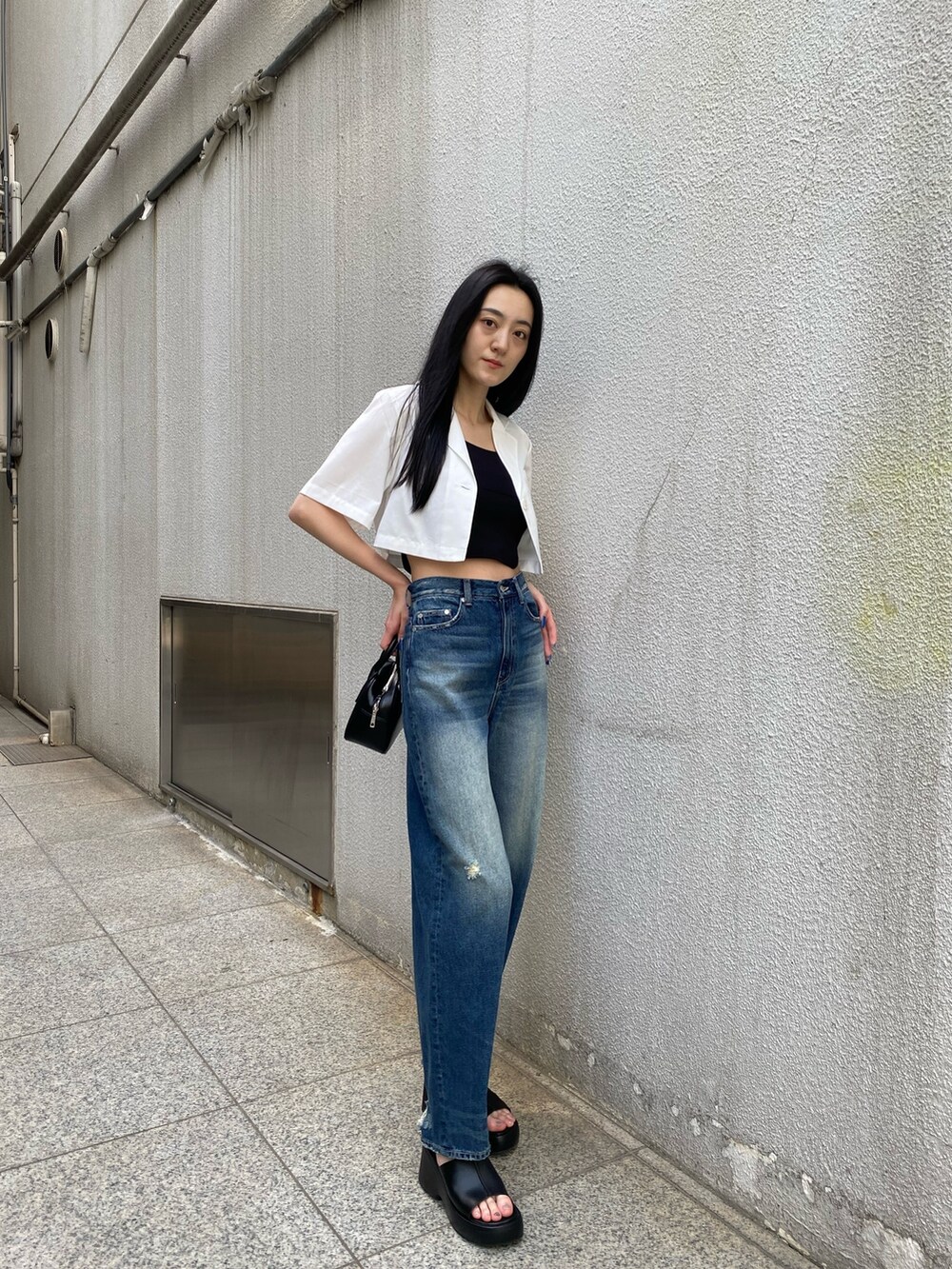 ブルー系のデニムパンツ、ブラック系のニット/セーター、ホワイト系のシャツ/ブラウスを着用したレディースの春コーディネートの3枚目の写真