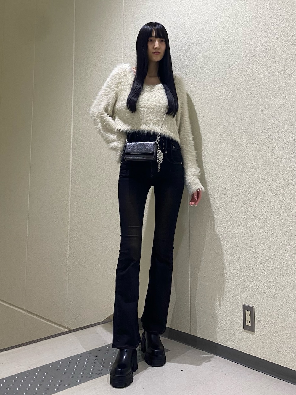 ホワイト系のニット/セーター、ブラック系のブーツ、ブラック系のデニムパンツを着用したレディースの冬コーディネートの2枚目の写真